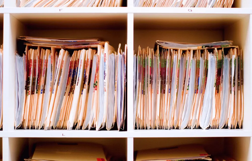 Shelves of paper medical record folders filed by letter